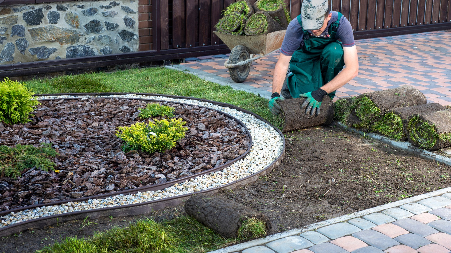 Mann verlegt Rollrasen für neuen Gartenrasen